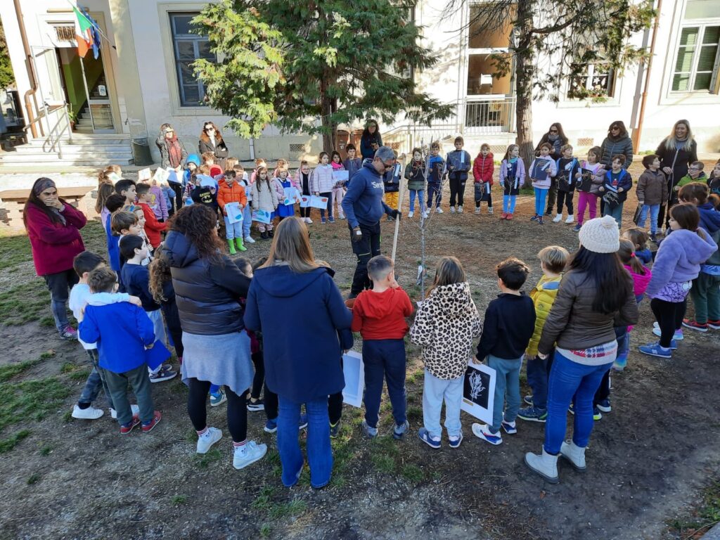 Bambini felici intorno a un albero, partecipando a un evento di piantumazione alberi.